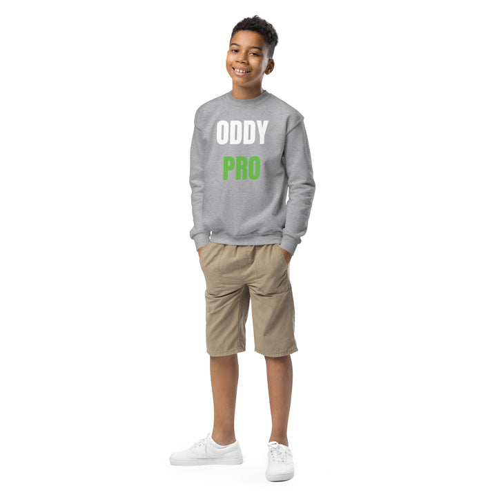 Boy wearing Oddy Pro Youth crewneck sweatshirt in gray with khaki shorts and white sneakers, smiling.